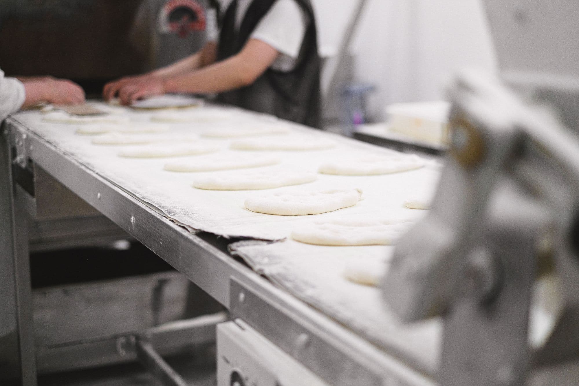 Dough portions on a floured conveyor in a food production facility
