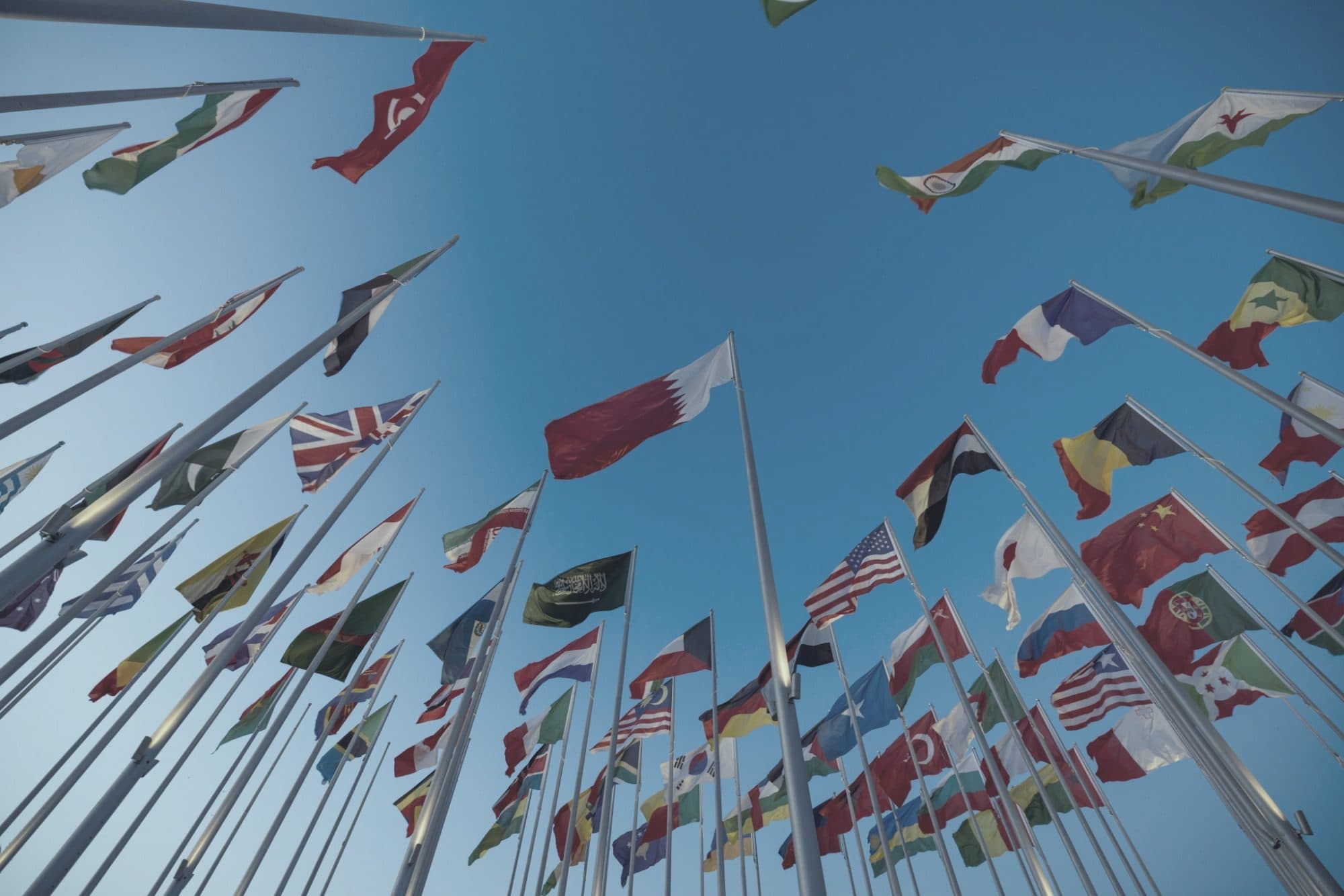 National flags from many countries flying against a blue sky, representing multiple jurisdictions